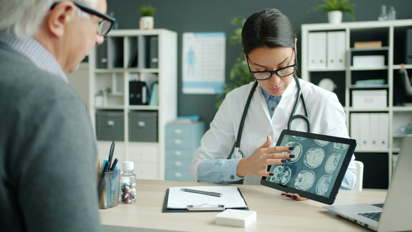 Medico che spiega delle scansioni mediche su un tablet a un paziente.